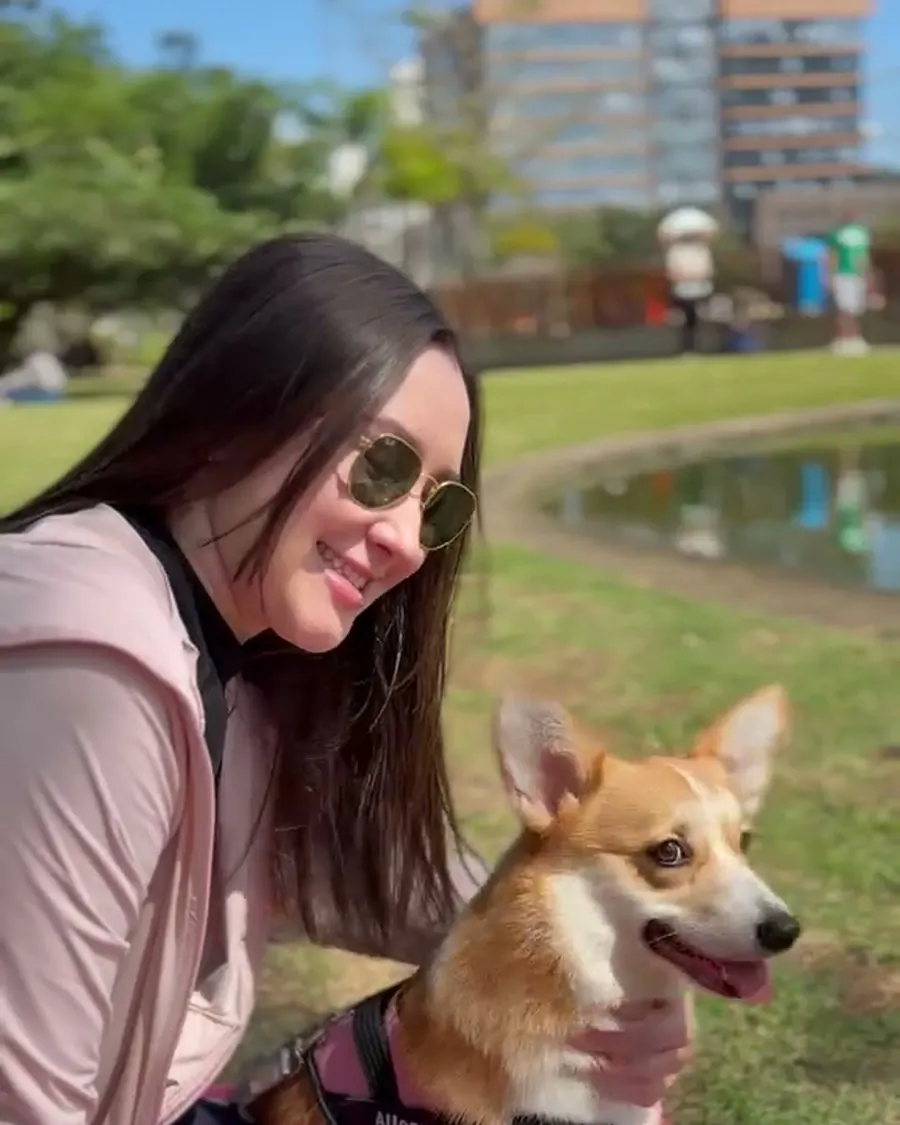 Dueña sonriendo con su corgi en el parque